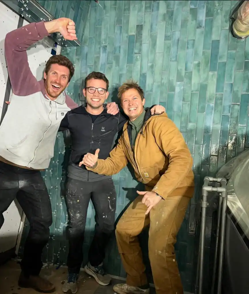 Three guys who are happy because they have finished building a café wall at Amager Strandpark Café on the pier.