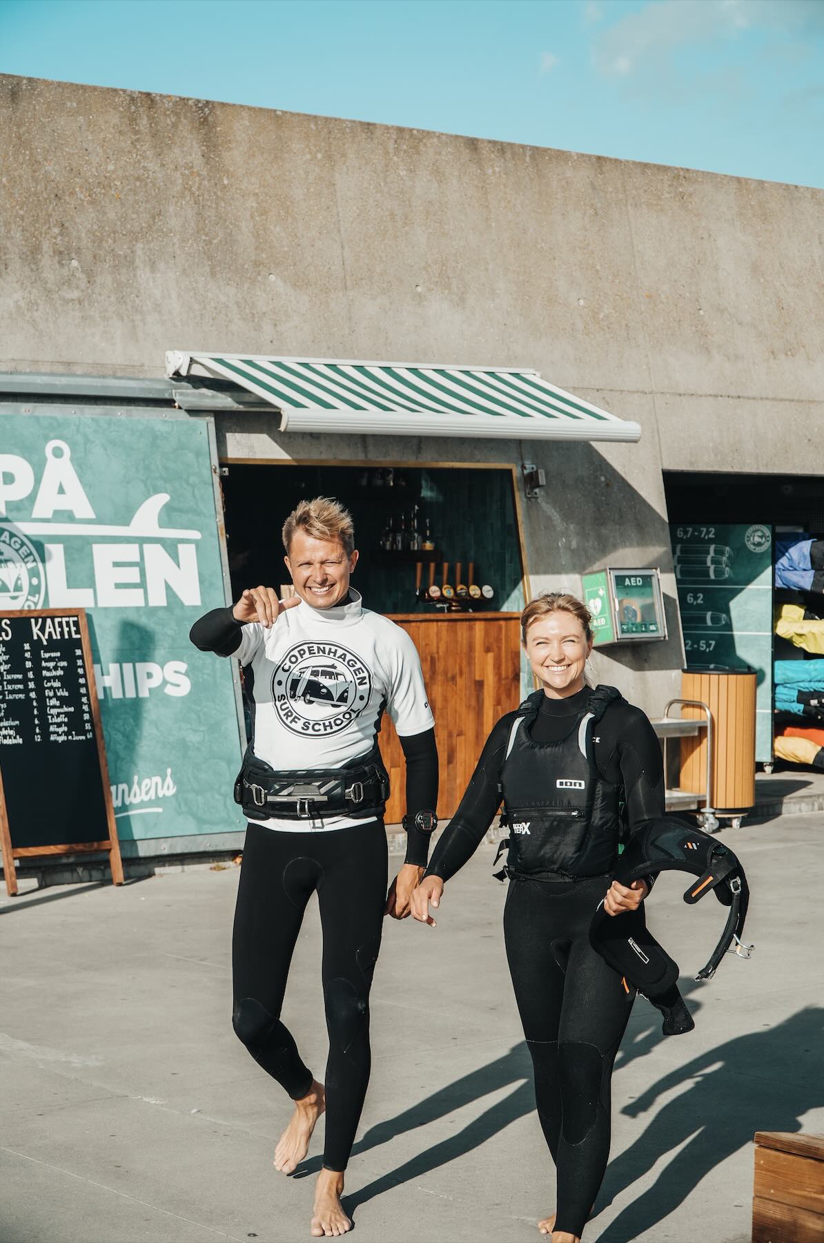 To surfere i våddragter på molen i Amager Strandpark på vej ud for at windurfe