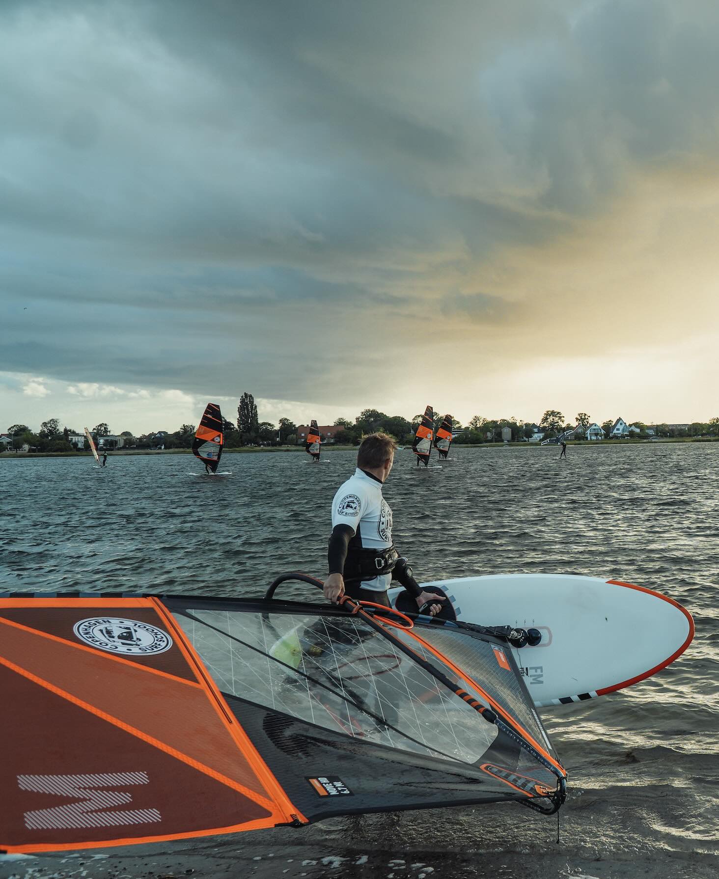 En windsurfer står i Amager Strandpark med sit surfudstyr og kigger ud over vandet